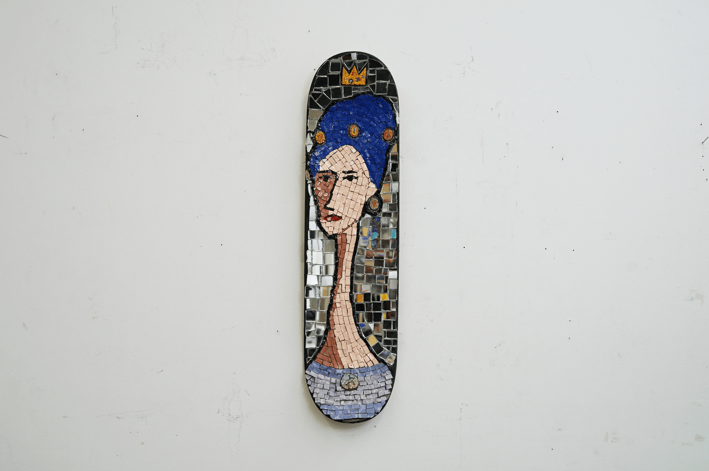 decorative mosaic on a skateboard deck of woman with blue hair and jewels