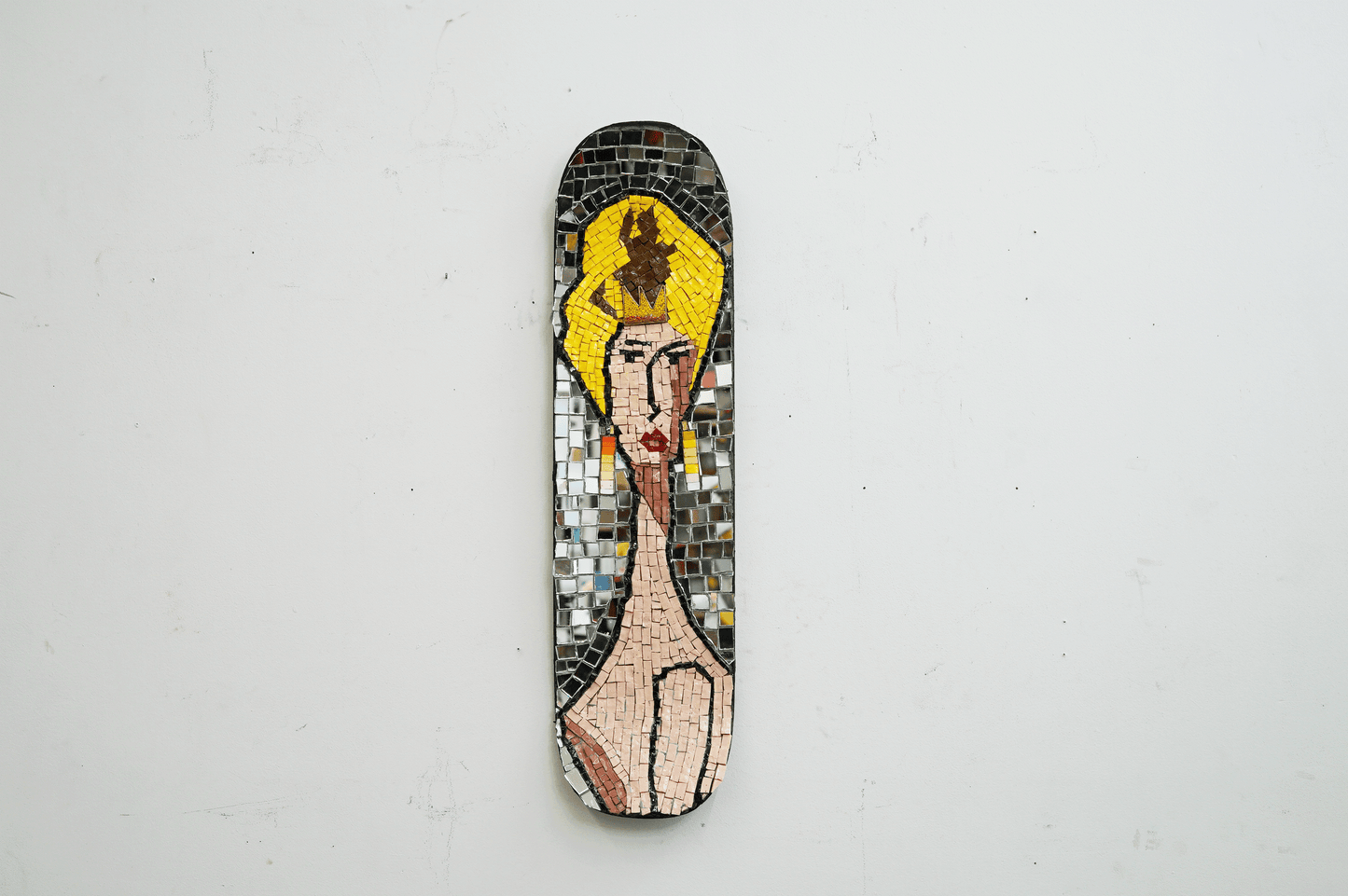 mosaic on a skateboard of a blonde woman with a yellow crown and earrings