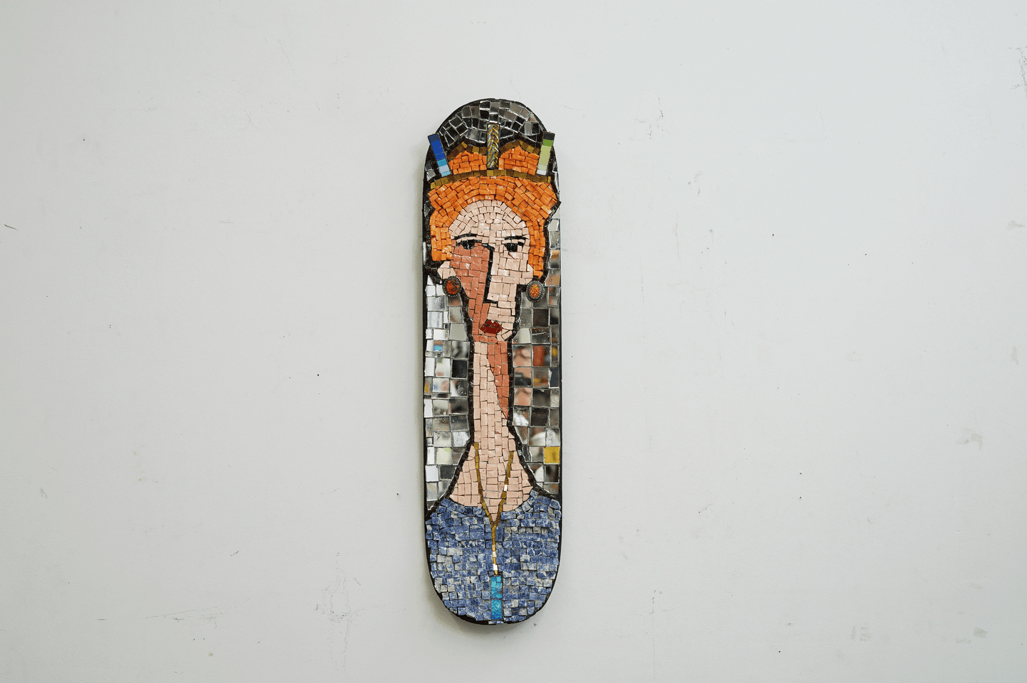 decorative mosaic on a skateboard deck of a red hair woman with a crown and jewels